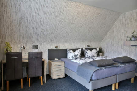 Modern eingerichtetes Doppelzimmer im Hotel Zur Brücke mit Schreibtisch, Stühlen und dekorativen Details unter einer Dachschräge
